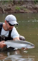 Fly fisherman holding river caught steelhead in Washington
